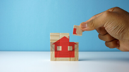 Conceptual of buying home. A man putting a last pieces of wooden block to complete the house icon.