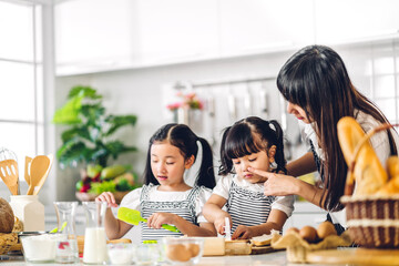 Portrait of enjoy happy love asian family mother and little toddler asian girl daughter child having fun cooking together with baking cookie and cake ingredient on table in kitchen