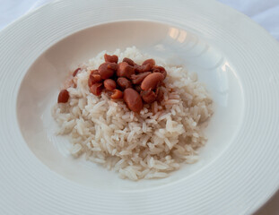 White rice with stewed red beans on a white plate.