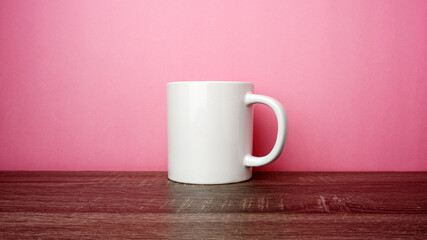 Fototapeta na wymiar Empty white cup on top of the wooden table on pink background. 