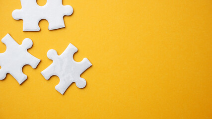 White jigsaw puzzle pieces in yellow background
