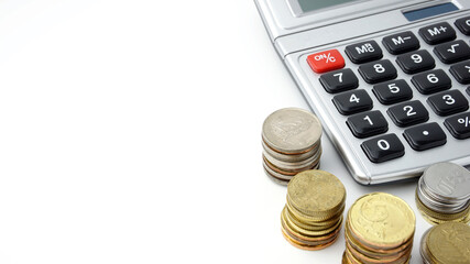 Economy or finance concept. Coins and calculator on the white background close up. Selective focus on coins.
