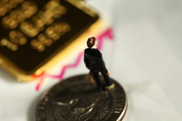Miniature figure model of businessman and real gold bar represent business concept related idea.