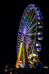Rueda de la fortuna en una feria de pueblo de noche con luces de colores brillantes y vivos 