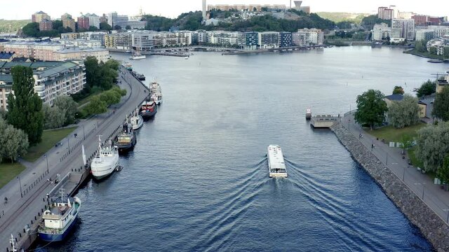Stockholm, Sweden. Aerial Drone hovering still with a summer view of a lake and bay at Hammarby Sj&ouml;stad with modern architecture, sightseeing boat, and docks with old houseboats.
