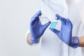 Two vaccine bottles in female doctor hands in protective gloves