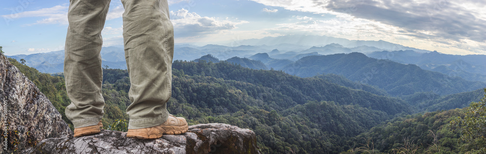 Wall mural hiker standing on top mountain sunset background. hiker men's hiking living healthy active lifestyle