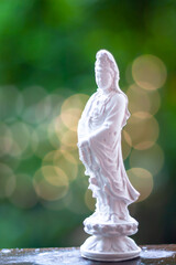 View of standing white Guan yin (Guanyin, goddess of mercy) statue isolated on blurred background.