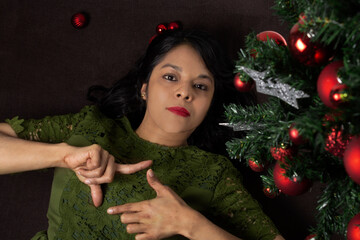 Joven mujer recostada junto a árbol de navidad.