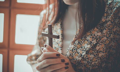 a woman is praying and holding a cross