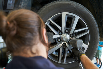 Mechanic male use air gun try to remove nut wheel for replace tires in car service garage