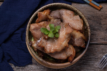 Roast pork in a ceramic cup on a wooden floor