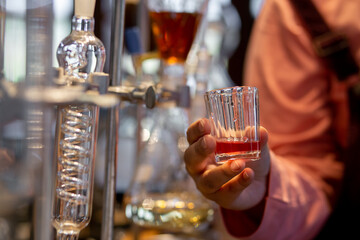 A close-up of fruit juice in a clear, distilled glass In the hands of the woman in the lab