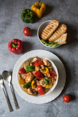 Top view of Chicken pieces and bell peppers in a bowl along with bread with use of selective focus.