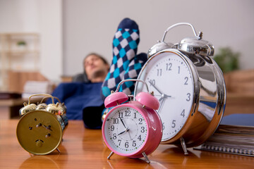 Young male employee sleeping in the office in time management co