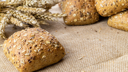 Bakery products. Rye bakery with crusty loaves and crumbs. Fresh loaf of rustic traditional bread with wheat grain ear or spike plant on natural cotton background. Concept - Cooking at Home.
