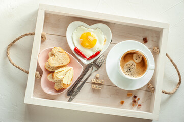 Breakfast on Valentine's Day Breakfast for your loved one On a tray a cup of coffee and two plates in the shape of a heart with scrambled eggs and toast and an inscription I love you. View from above.