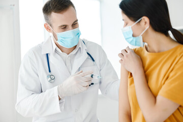 doctor hold syringe in hand medical mask female patient in yellow t-shirt covid vaccination