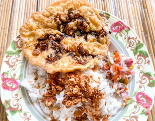 rice with fried egg, fried onion and sambal matah, indonesian food served with rattan background.