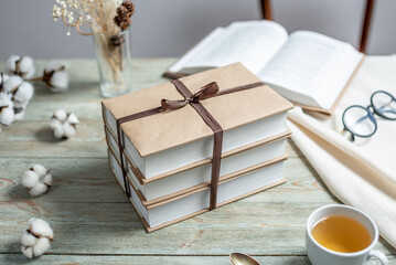 Cute stack of books with craft paper covers, tied with ribbon on a wooden table. Concept of reading...