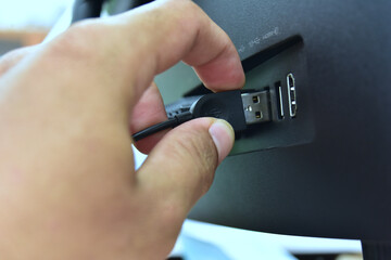 Unplugging USB cable from computer. Disconnect USB cord from the computer. Man hold USB plug against computer.