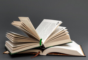 Stack of opened books on black background.