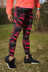 Active woman wearing sports clothes stretching in the grass after workout.