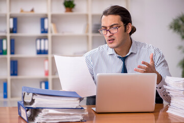Young male employee unhappy with excessive work in the office
