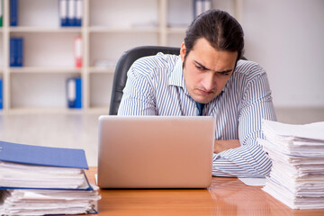 Young male employee unhappy with excessive work in the office