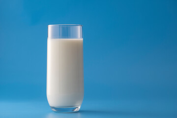 Glass of white milk isolated on blue background
