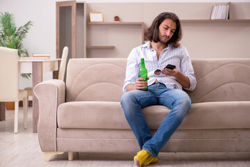Fototapeta premium Young man drinking alcohol at home
