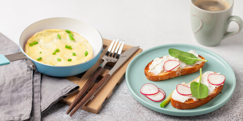 Healthy breakfast - omelette with green onions, toast with cream cheese and vegetables, coffee