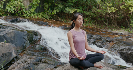 Sport woman do yoga at waterfall