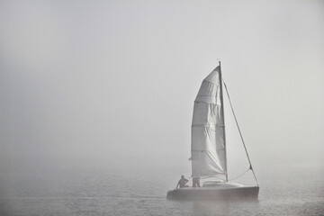 A sailing boat in the mist and foggy weather on the water