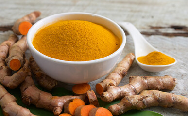 Turmeric (curcumin) powder in a white bowl and turmeric root on a wooden table,For cooking,copy space.