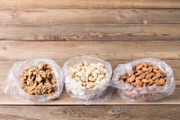 Superfoods walnut, almond, cashew in plastic bags on a wooden background.
