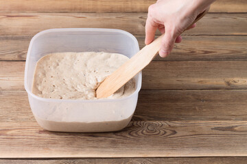 Rye sourdough on flour sourdough in a container on a wooden table. Fermentation.