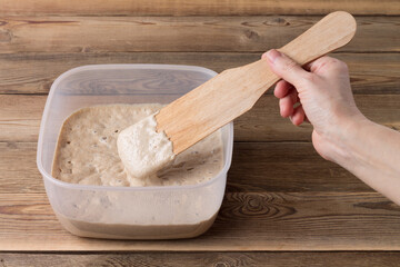 Rye sourdough on flour sourdough in a container on a wooden table. Fermentation.