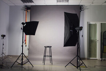 Photo studio interior with a gray background and two soft box lighting.