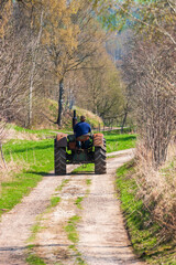 Old tractor driving on a dirt road in the spring
