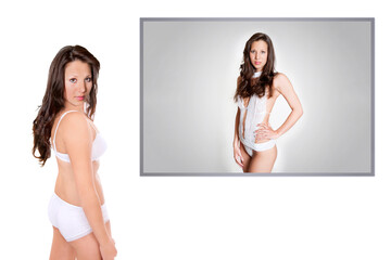 Beautiful young lingerie model in front of an underwear photo of herself, isolated on white...