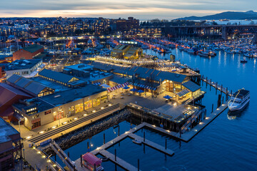 Granville Island Public Market, Marina and Fishermen's Wharf Float in dusk. Vancouver city buildings skyline in the background. Vancouver, Canada.