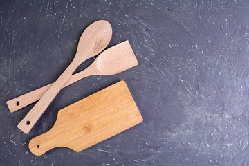 Culinary background. Wooden spoon and spatula on a dark textured background.Selective focus.