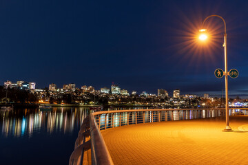 Pedestrian and bicycle shared route sign and pathway at night. Vancouver downtown Seaside Greenway coastal area walking path.