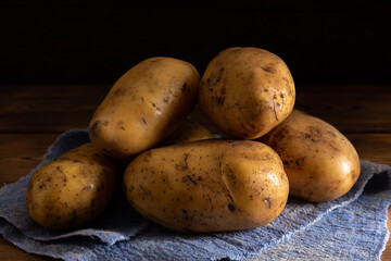 Group of potatoes on blue fabric on dark background.