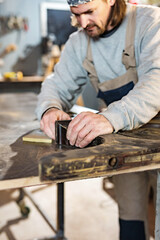 Obraz na płótnie Canvas Male carpenter working on old wood in a retro vintage workshop.