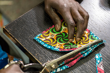 Details of tailor's hands while working, close up of the process of making handycraft face masks,...
