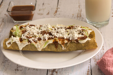 Traditional Mexican food, golden meat tacos (flautas) with red sauce.