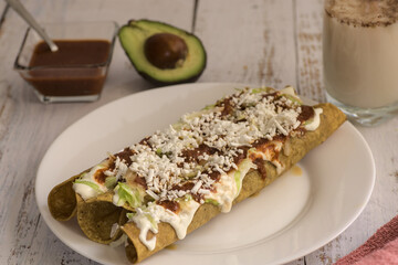 Traditional Mexican food, golden meat tacos (flautas) with red sauce.