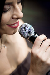 Beautiful caucasian woman singing with the microphone on the scene.